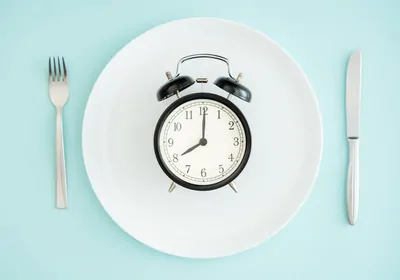 Photo of a clock on a plate with cutlery on either side.